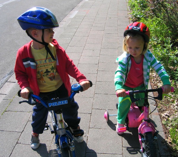 Toddlers riding a bike at home